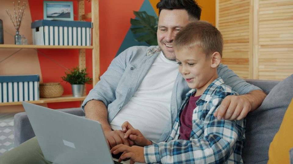 Father and adolescent son working together on computer